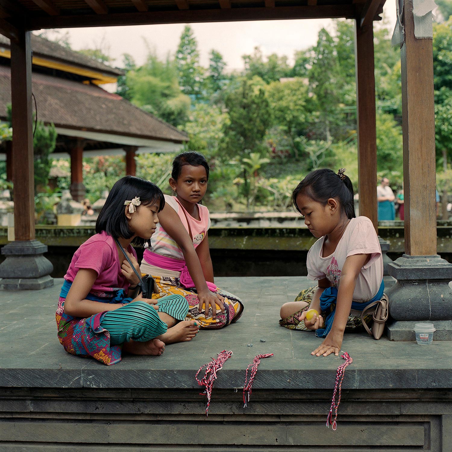 Three young girls at temple playing a game.