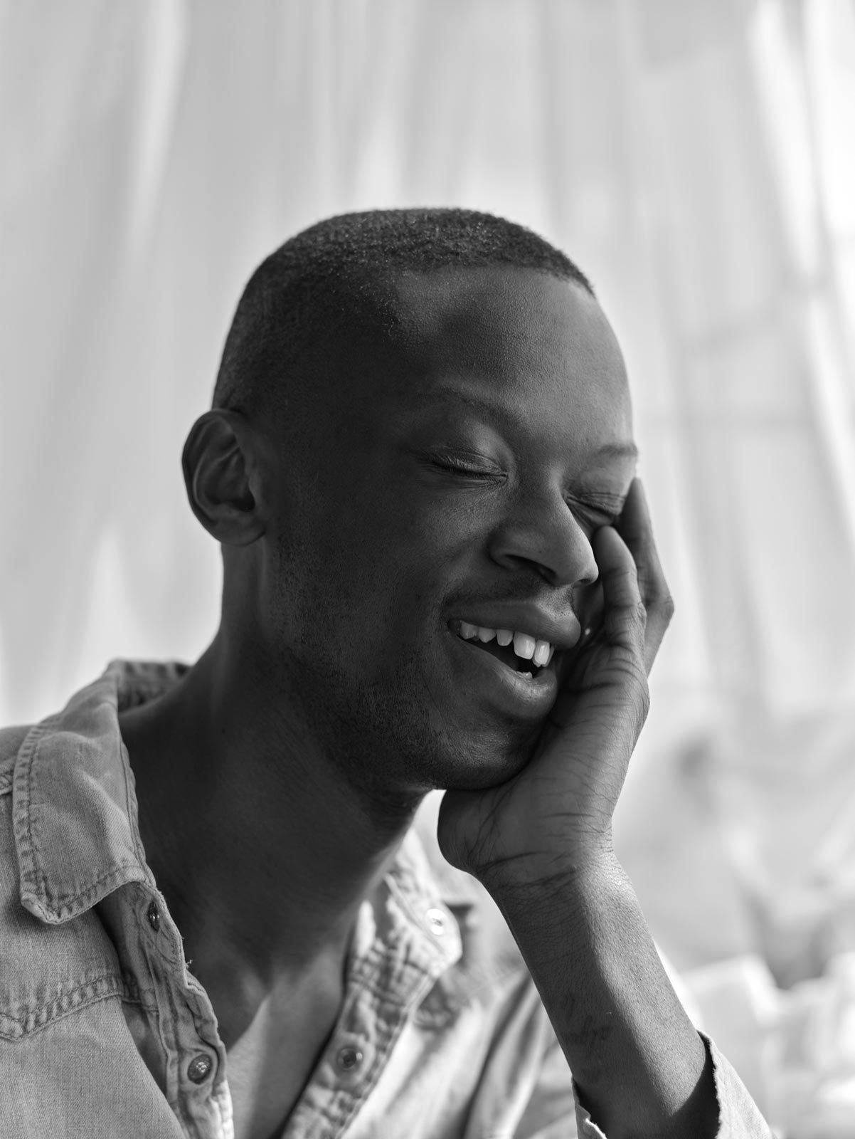 Male fashion model caught laughing during a portrait shoot, black and white photography.