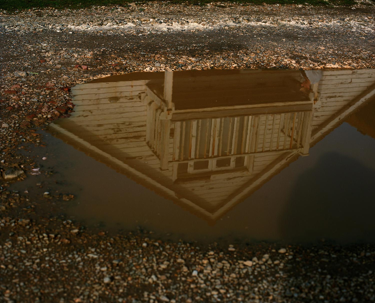 Reflection of a house in a merky puddle, analogue photography.