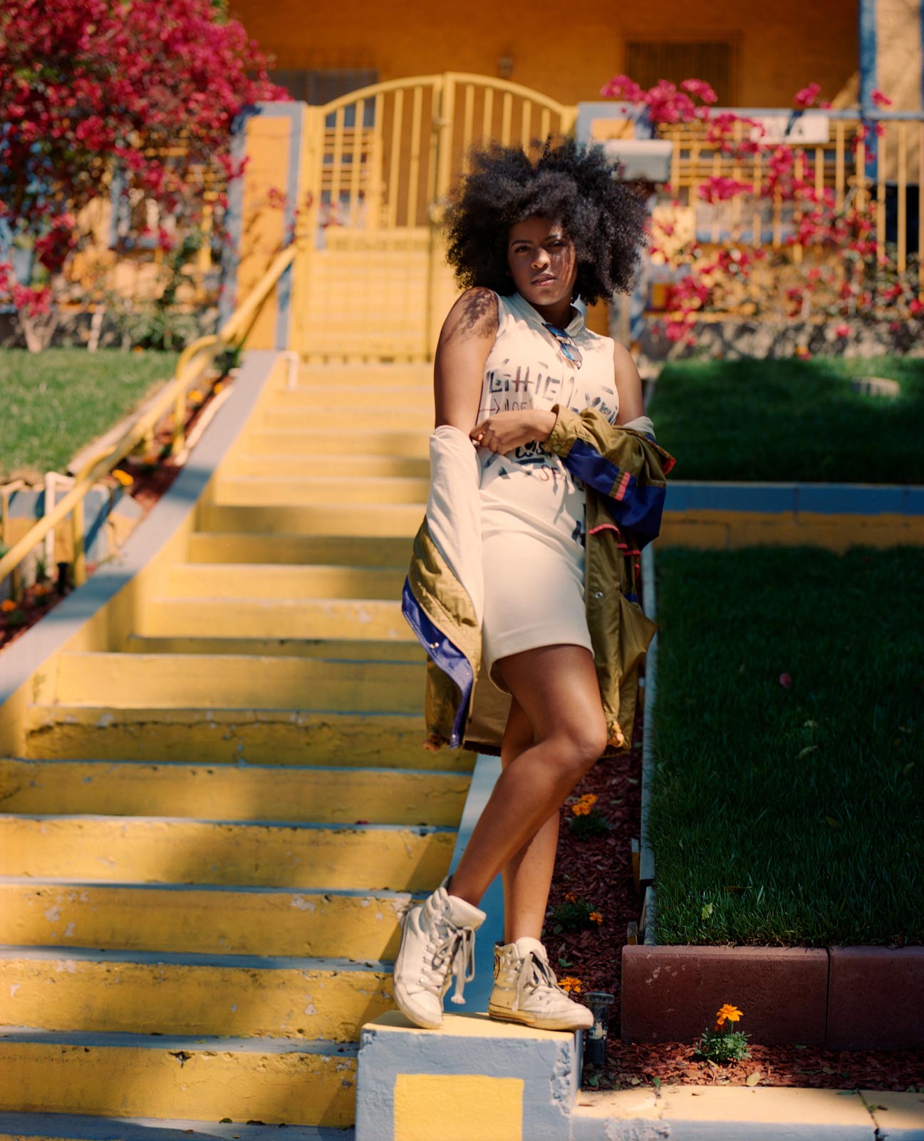 Rebel Rae, Singer, posing infront of yellow house, LA.