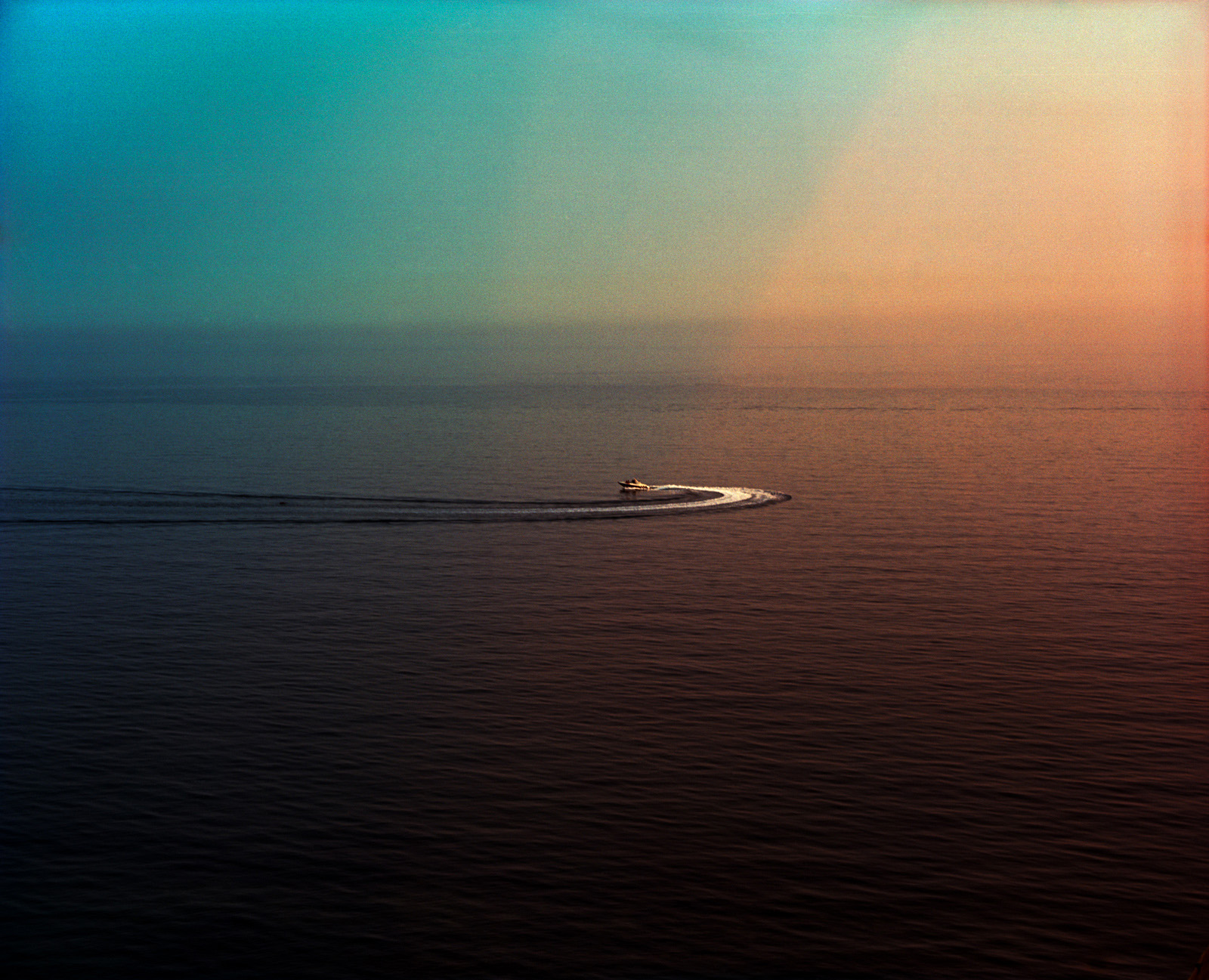 Speed boat on the open sea at sunset, analogue photography.