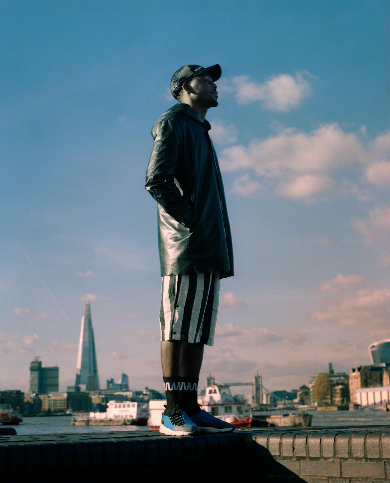 Emmanuel Lawal, Man standing on a wall, infront of view of the London Skyline for What We Wear SS18.